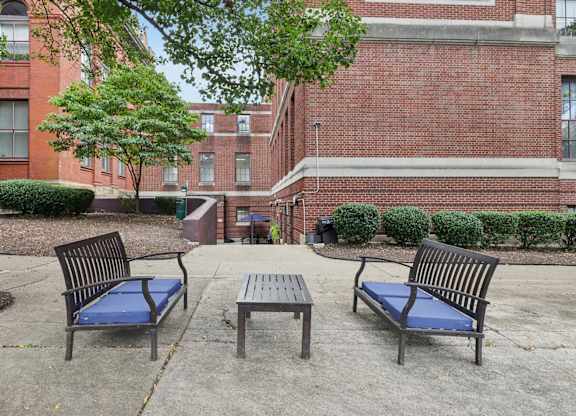 A park area with a bench, table and a tree.