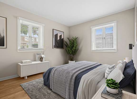 A bedroom with a bed, nightstand, and a plant.
