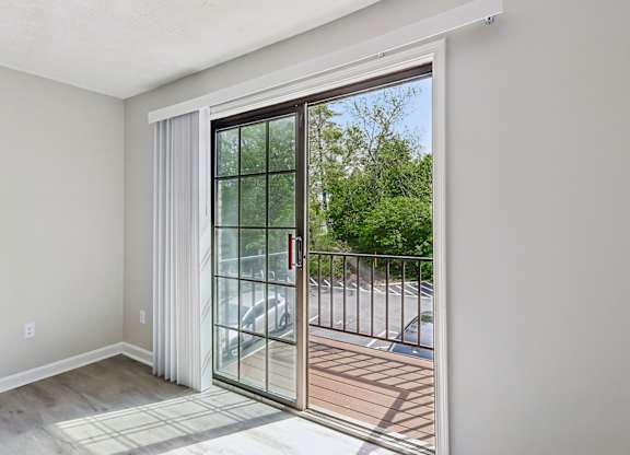 A room with a sliding glass door leading to a balcony.