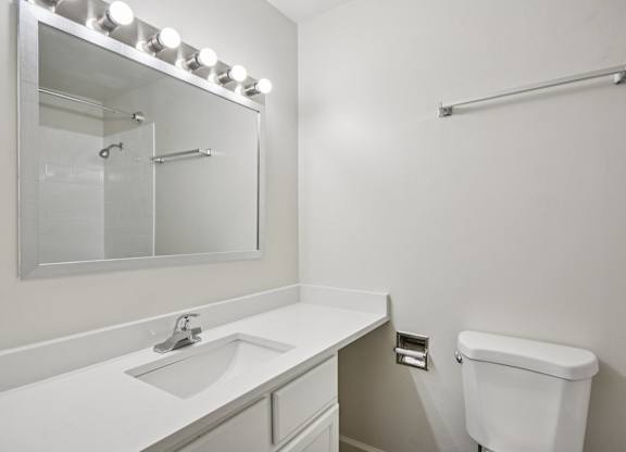 A white bathroom with a sink, toilet, and mirror.