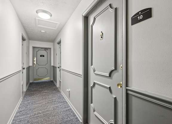 A hallway with a door on the right and a sign on the wall.
