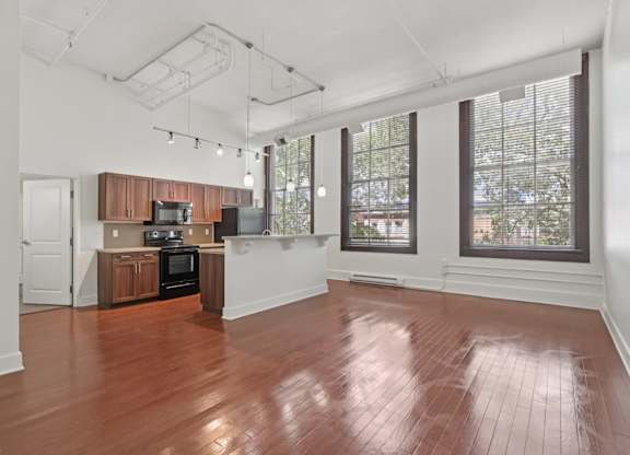 A large living room and kitchen with wooden floors and white walls.