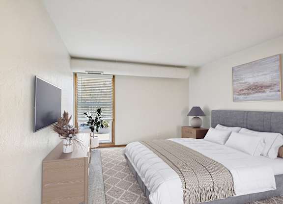 A bedroom with a large bed and a television on the wall.