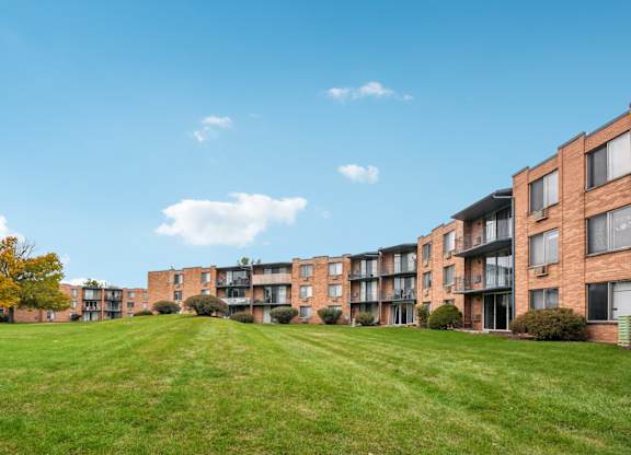 A row of apartment buildings with a green lawn in front.