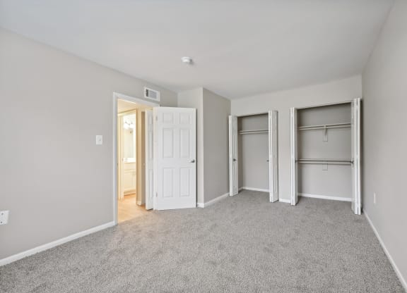 a bedroom with a carpeted floor and two closet doors at ReNew Odenton