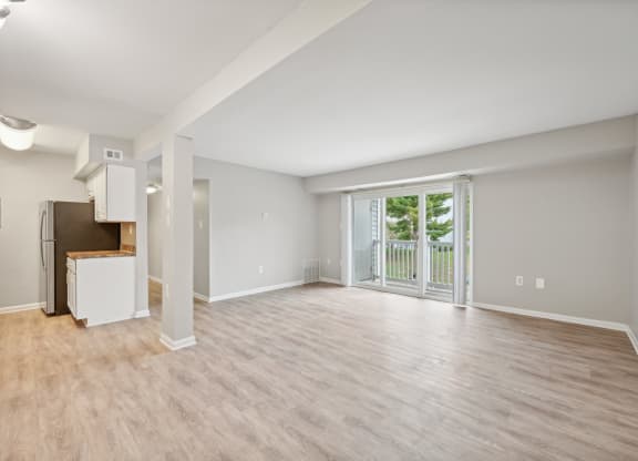 an empty living room with a sliding glass door to a balcony at ReNew Odenton