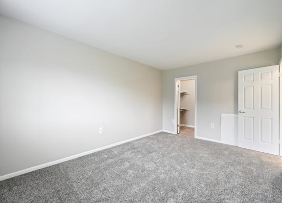 an empty bedroom with carpet and a door to a closet at ReNew Odenton