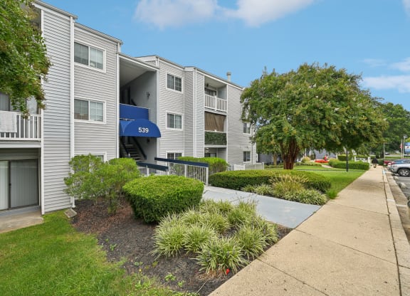 Exterior view of our apartments with a sidewalk and landscaping in front at ReNew Odenton