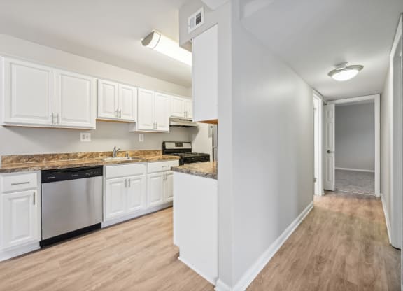 a kitchen with white cabinets and a counter top and looking into a hallway at ReNew Odenton