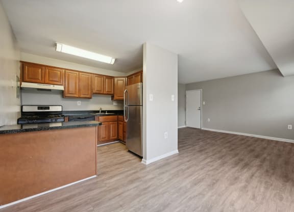 an empty kitchen with wood flooring and a stainless steel refrigerator and view into the empty dining room at ReNew Odention