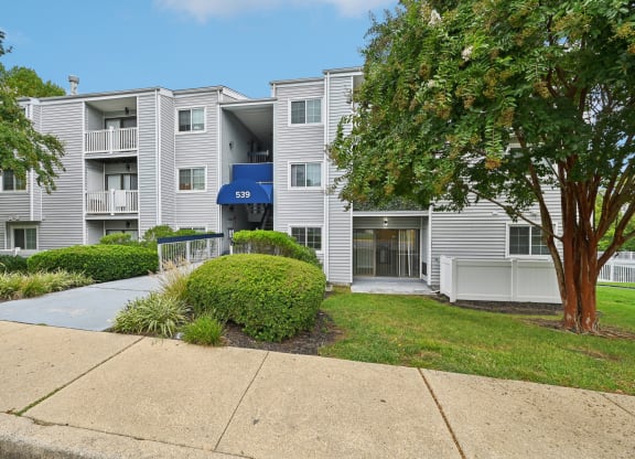 an apartment building with white siding and a sidewalk at ReNew Odenton