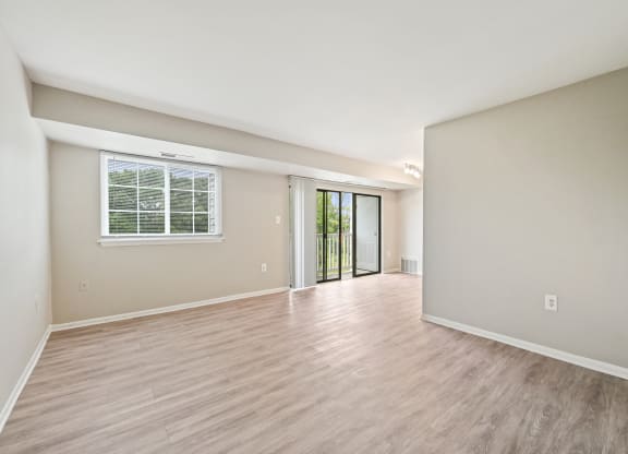 the living room and dining room of an empty house with wood flooring at ReNew Odenton