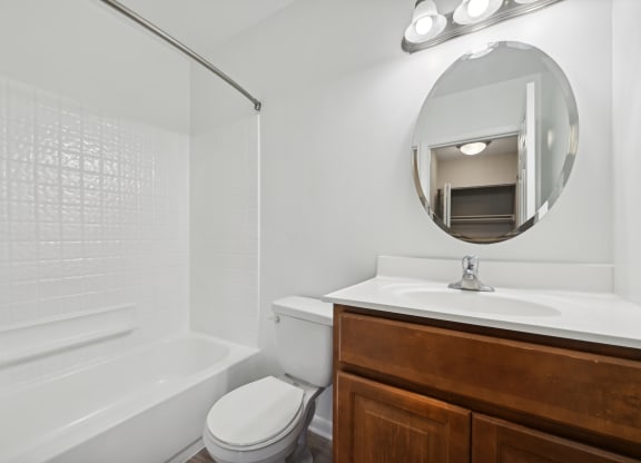 a bathroom with a toilet and sink with mirror and shower at ReNew Odenton