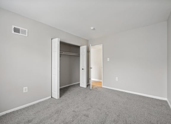 a bedroom with carpet and an open door to a closet at ReNew Odenton