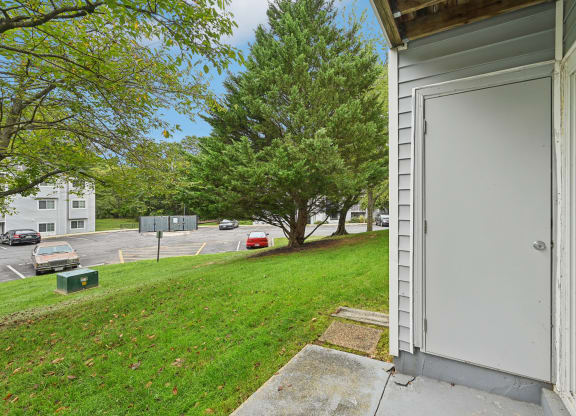 the front door of an apartment building with a lawn and trees at ReNew Odenton