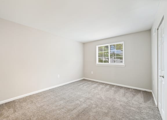 an empty bedroom with carpet and a window at ReNew Odenton