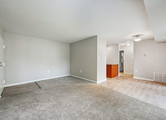 the living room and dining room in a new home with white walls and wood floors at ReNew Odenton