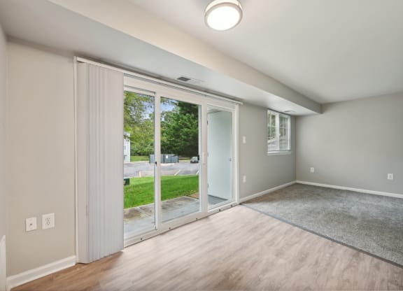 an empty living room with sliding glass doors to a yard at ReNew Odenton