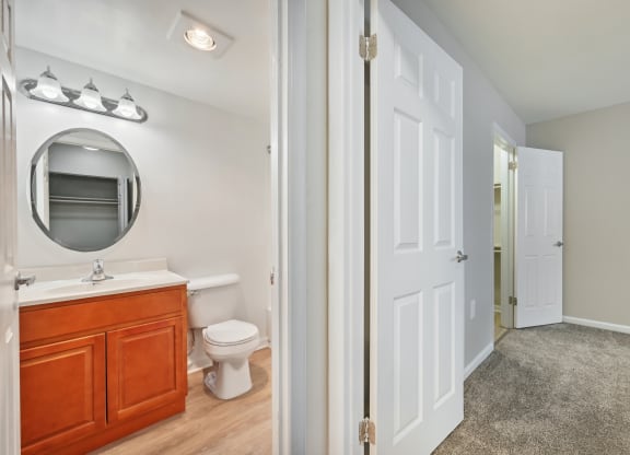 view into a bathroom with a mirror, a toilet and a sink from a hallway at ReNew Odenton
