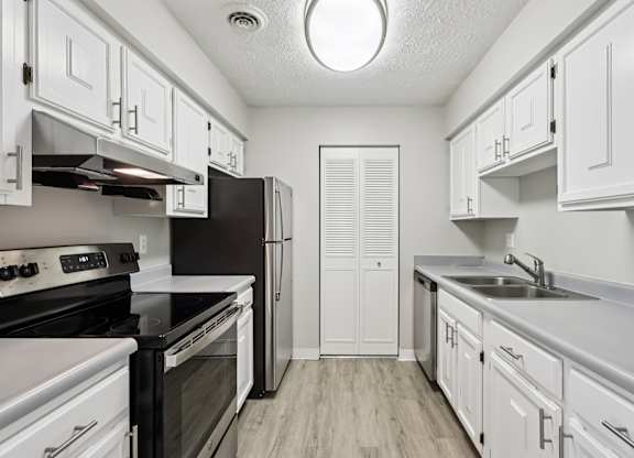 A kitchen with white cabinets and black countertops.