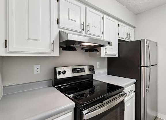 A kitchen with white cabinets and a black refrigerator.