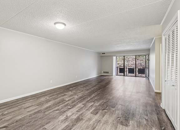 A room with wooden flooring and a window with blinds.