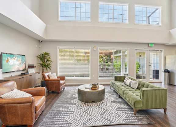 A sitting room with a brown leather couch, a green sofa, and a coffee table in the center.