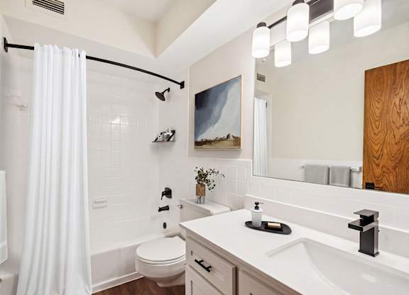 A white bathroom with a white toilet, a white sink, and a white shower curtain.