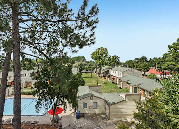 A pool surrounded by trees and apartment buildings.