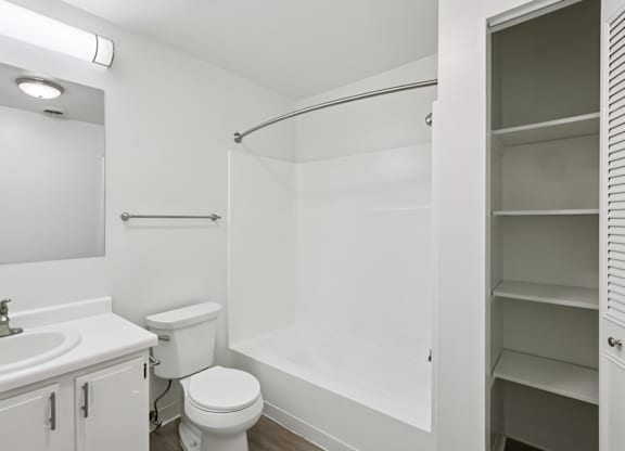 A white bathroom with a toilet, sink, and shower.