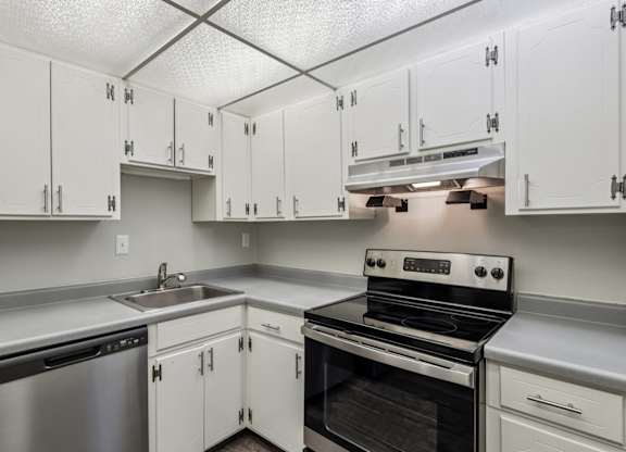 A kitchen with white cabinets and a stove top oven.