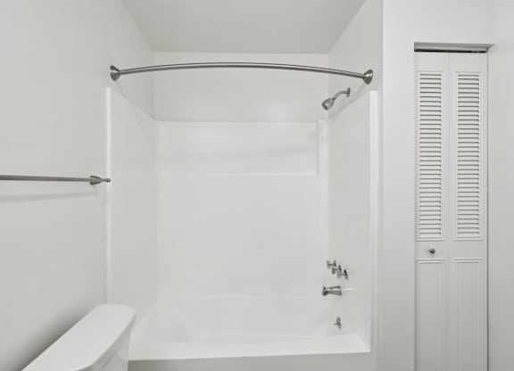 A white bathroom with a tub and a towel rack.