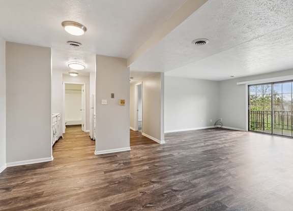 A spacious room with wooden flooring and white walls.