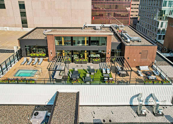 A rooftop patio with a pool and seating area.