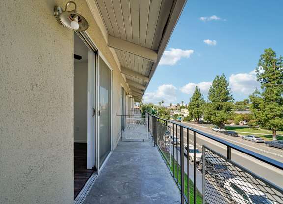 A balcony with a metal railing and a concrete floor.