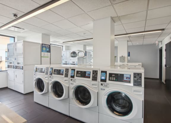 a laundry room with a row of washing machines and dryers