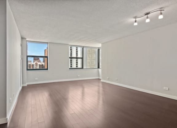 an empty living room with hardwood floors and a large window
