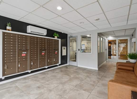 A lobby with a brown couch and a wall of mailboxes.