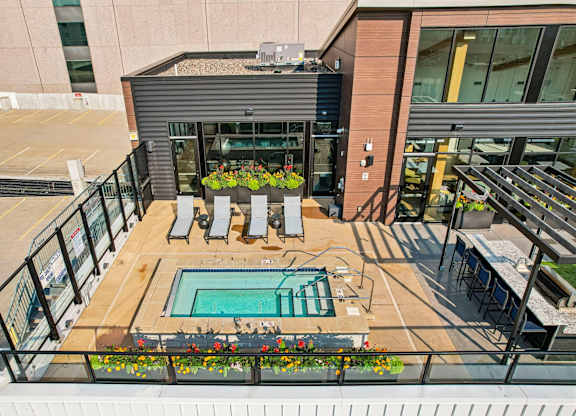 A small pool is surrounded by a deck with chairs and flowers.