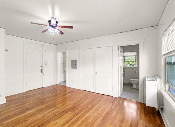 A room with a ceiling fan and wooden floors.