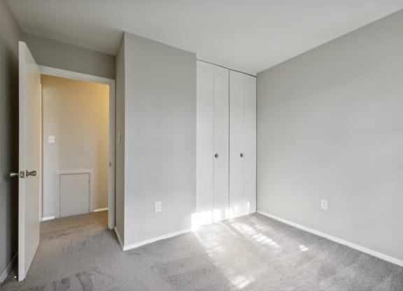 an empty bedroom with white cabinets and a door to a closet at Briarwood Apartments, Dumfries, Virginia