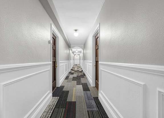 A long hallway with a striped carpet and white walls at Pleasant Oak Apartments, Illinois
