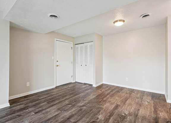 A room with a white door and a brown floor.