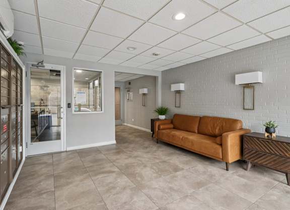 A lobby with a brown couch and a white wall.