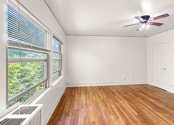 A room with a ceiling fan and a window with blinds.