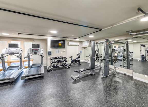 A spacious gym with a variety of equipment including treadmills, weights, and exercise machines. at Oak Park City, Oak Park, IL