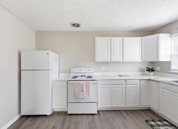 A white kitchen with a refrigerator, oven, and cabinets.