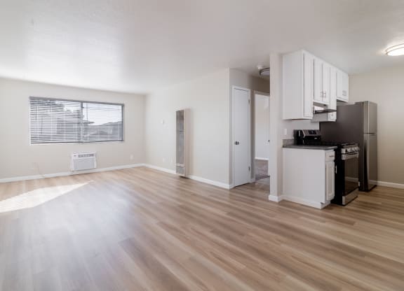 the living room and kitchen of an apartment with a hard wood floor at Alturas Paso Robles Apartment Homes, Paso Robles, CA