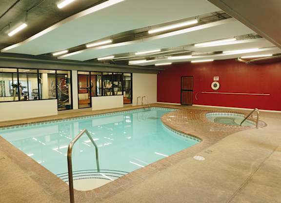 A swimming pool inside a building with a red wall at Astor Place of Edina Apartments , Minnesota, 55435