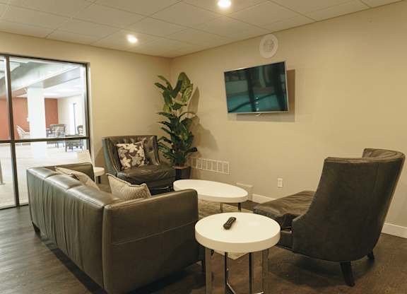 A living room with a brown couch, a white table, and a TV at Astor Place of Edina Apartments , Edina, 55435